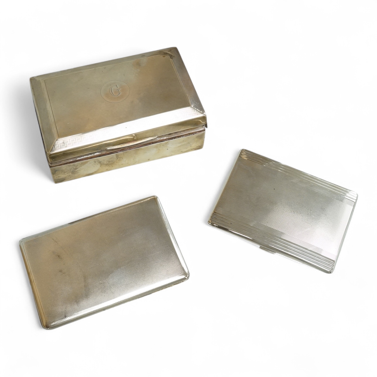 An engine turned silver rectangular cigarette box, 14.1cm and two mid 20th century engine turned silver cigarette cases.